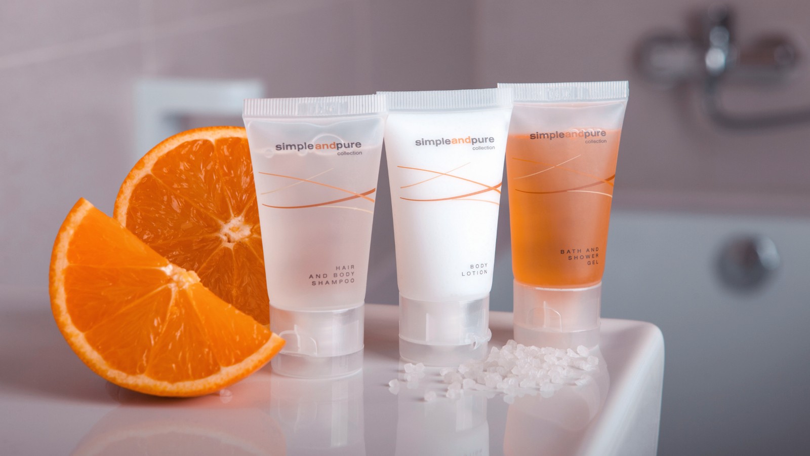 Elegant display of Simple And Pure luxury hotel cosmetics, with citrus and orange fragrance, featuring beautifully designed tubes of shampoo, conditioner, and lotion. These premium guest toiletries elevate the hotel amenities, offering a refined experience for guests.