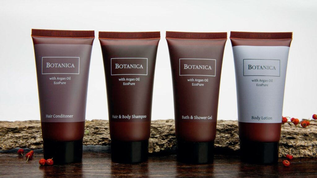 Four sleek brown tubes of 40ml from BOTANICA premium hotel toiletries collection. One tube is hair conditioner, one tube is hair and body shampoo, one tube is bath and shower gel, and one tube is body lotion. All toiletries are formulated with argan oil and are Eco pure.