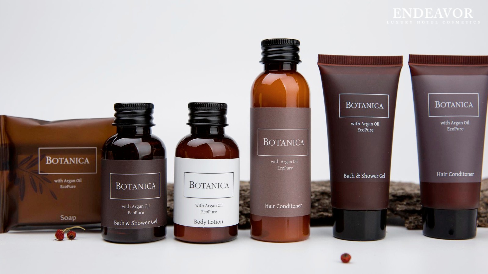 An elegant display of luxury hotel toiletries brand Botanica. Mini bottles of shower gel body wash, body lotion, hair conditioner, a soap bar wrapped in bag and shower gel, body wash, hair conditioner in mini tubes.