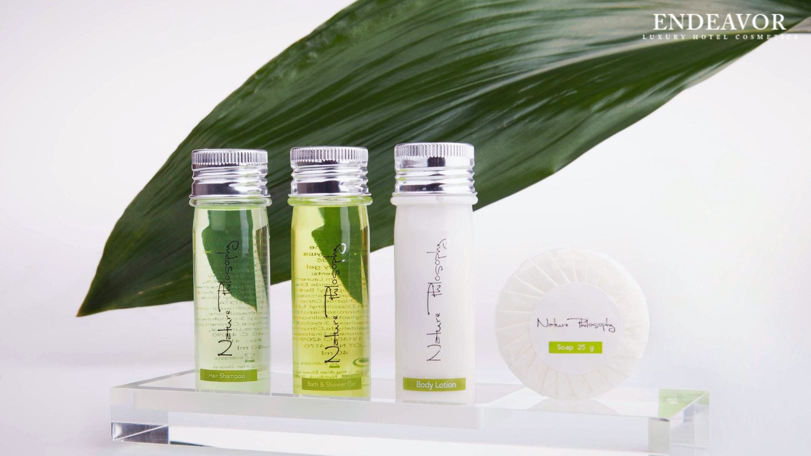 Elegant display of luxury hotel toiletries brand Nature Philosophy. Mini bottles of hair shampoo, bath and shower gel, body lotion a soap bar 25g wrapped in paper.