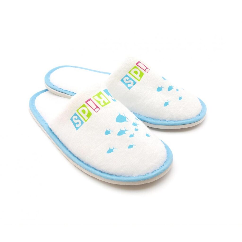 Soft and cozy white hotel slippers for kids with blue trim and playful fish design. Perfect for young guests' comfort. Ideal hotel amenities for families.